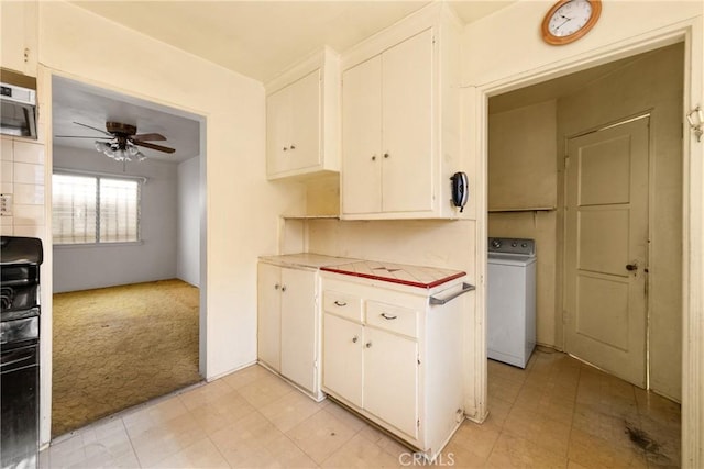 kitchen featuring ceiling fan, light colored carpet, white cabinets, and washer / dryer