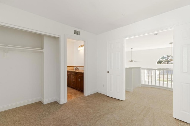 unfurnished bedroom featuring visible vents, baseboards, ensuite bathroom, a sink, and light colored carpet