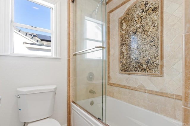 bathroom with toilet and bath / shower combo with glass door