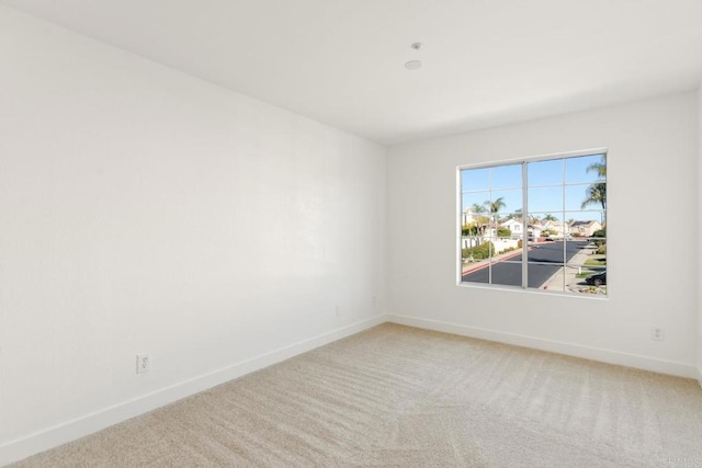 carpeted empty room featuring baseboards