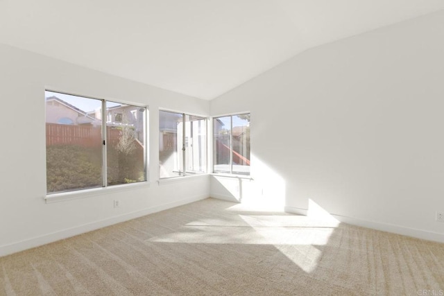 empty room featuring carpet, baseboards, and vaulted ceiling