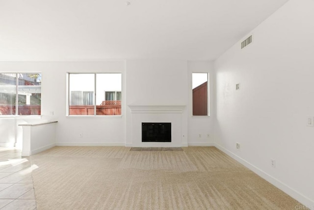 unfurnished living room featuring a fireplace with flush hearth, visible vents, light colored carpet, and baseboards