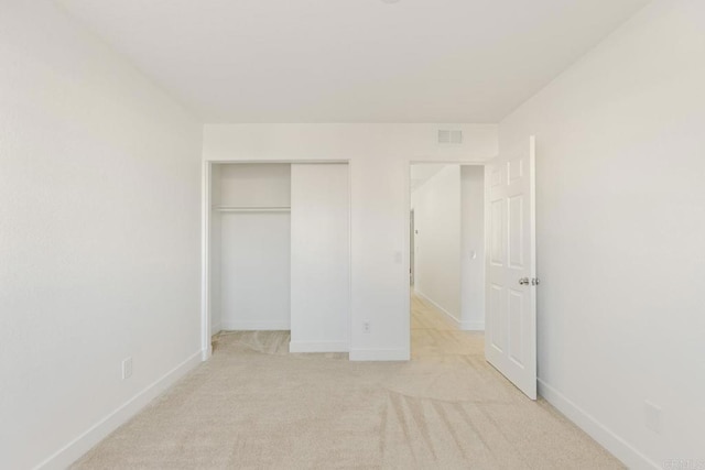 unfurnished bedroom featuring light carpet, baseboards, and a closet