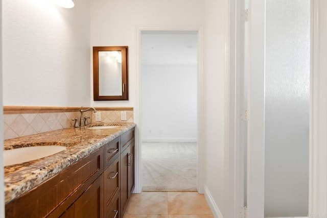 bathroom featuring backsplash, double vanity, a sink, and tile patterned flooring