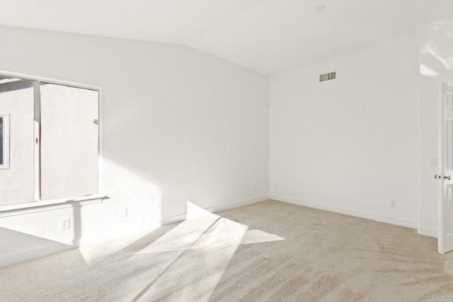spare room with baseboards, lofted ceiling, visible vents, and carpet floors