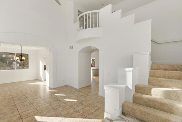 staircase with arched walkways, visible vents, tile patterned flooring, and a notable chandelier