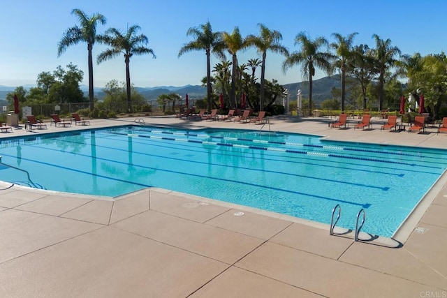 community pool featuring fence, a patio area, and a mountain view