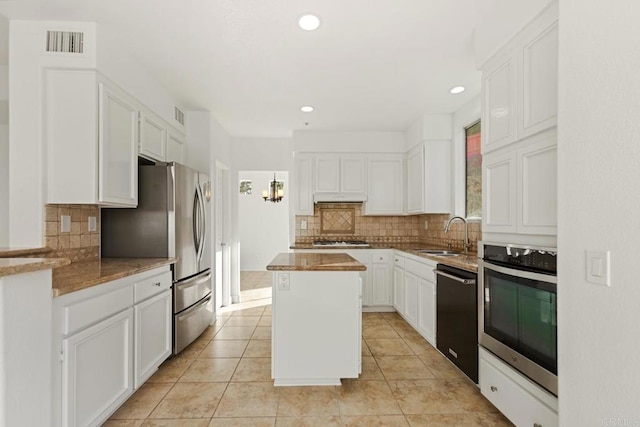 kitchen with visible vents, a center island, a sink, appliances with stainless steel finishes, and decorative backsplash