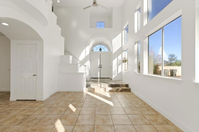 tiled entryway with baseboards, arched walkways, a high ceiling, ceiling fan, and recessed lighting