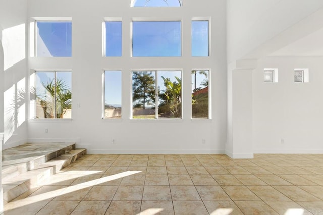 unfurnished living room with a high ceiling, tile patterned flooring, and plenty of natural light