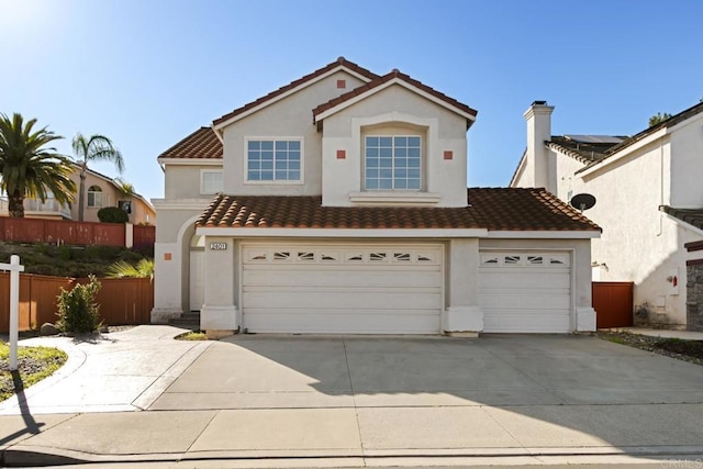 view of front of property with a tiled roof, stucco siding, fence, an attached garage, and concrete driveway