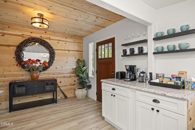 bar with wooden ceiling, light stone countertops, light hardwood / wood-style floors, and white cabinets