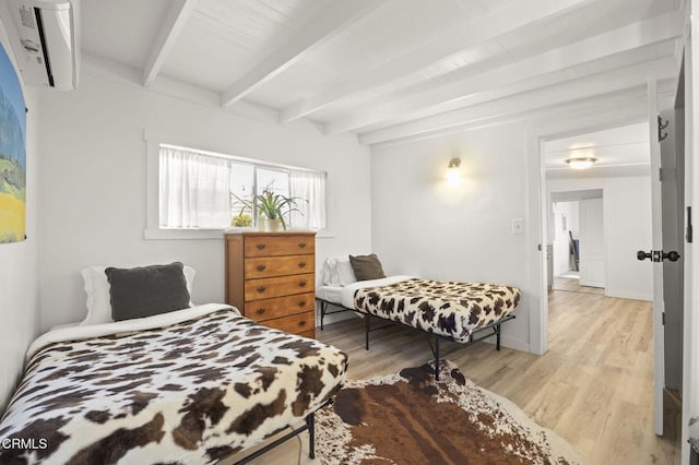 bedroom featuring beam ceiling, a wall mounted AC, and light wood-type flooring