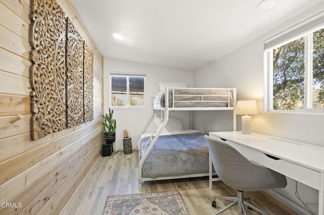 bedroom with light hardwood / wood-style flooring and wooden walls