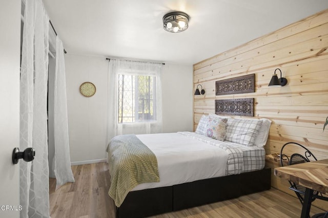 bedroom featuring wooden walls and light hardwood / wood-style flooring