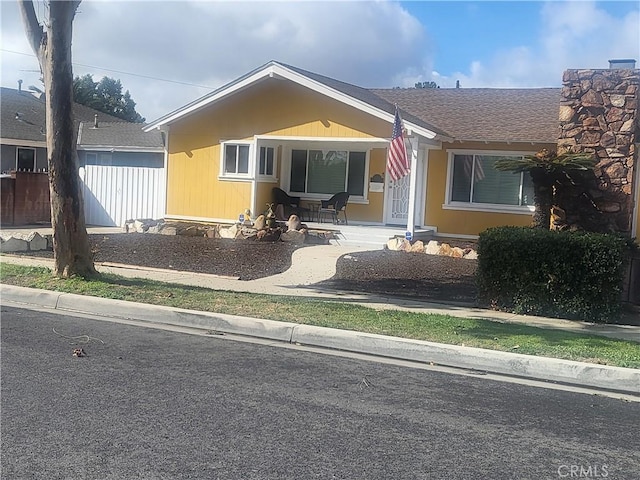 view of front of house featuring a shingled roof and fence