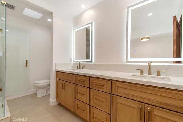 bathroom featuring a sink, toilet, a stall shower, and tile patterned floors
