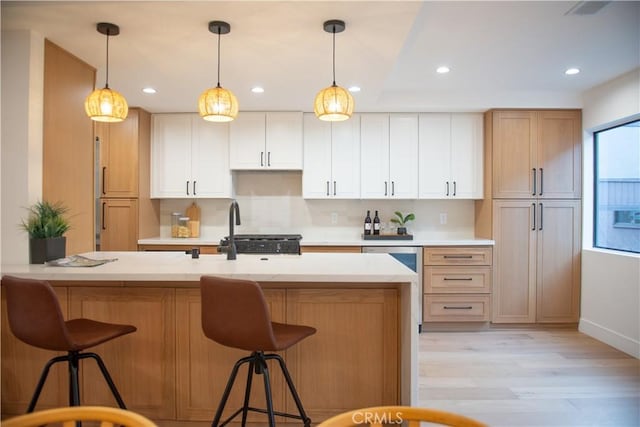 kitchen with light wood finished floors, pendant lighting, a breakfast bar, and a sink