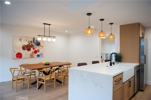 kitchen with light wood finished floors, recessed lighting, a sink, hanging light fixtures, and appliances with stainless steel finishes