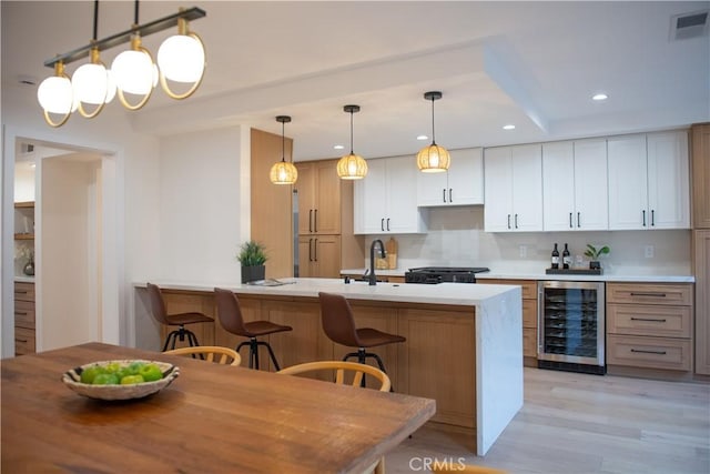 kitchen with visible vents, beverage cooler, tasteful backsplash, light wood-style floors, and a peninsula