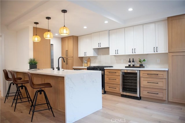 kitchen featuring a breakfast bar, wine cooler, light wood-style floors, a peninsula, and stainless steel gas range