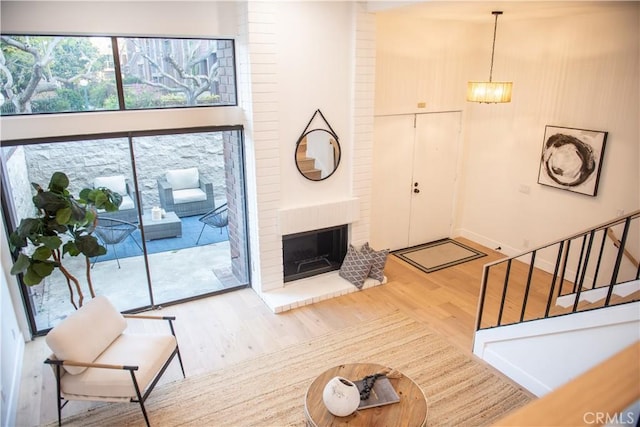 living area featuring stairway, a brick fireplace, and wood finished floors