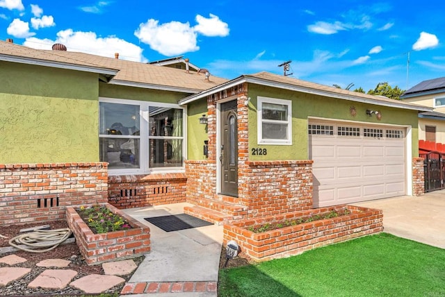 doorway to property featuring concrete driveway, brick siding, an attached garage, and stucco siding