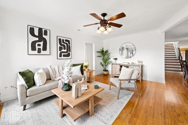 living room with stairs, ceiling fan, light wood finished floors, and baseboards