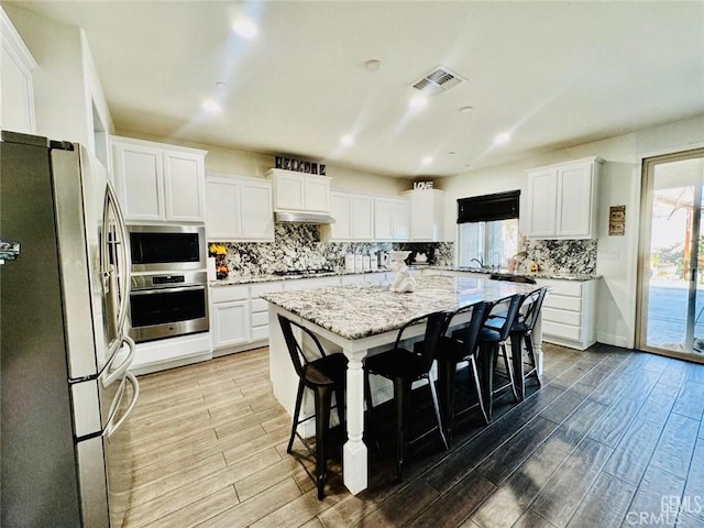826 Jacob Creek Dr, Bakersfield, CA 93314 - kitchen featuring a center island, a kitchen breakfast bar, stainless steel appliances, light stone countertops, and white cabinets
