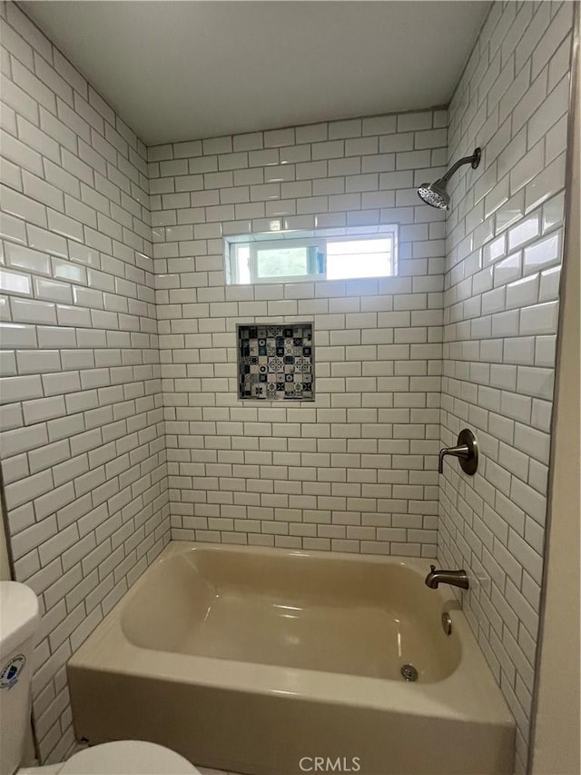 bathroom featuring tiled shower / bath combo and toilet