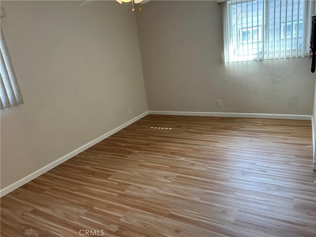 spare room featuring wood finished floors, baseboards, and ceiling fan