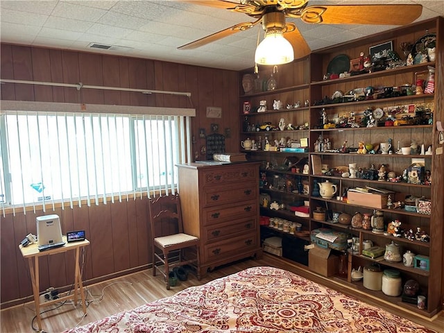 sitting room featuring visible vents, wood walls, ceiling fan, and wood finished floors