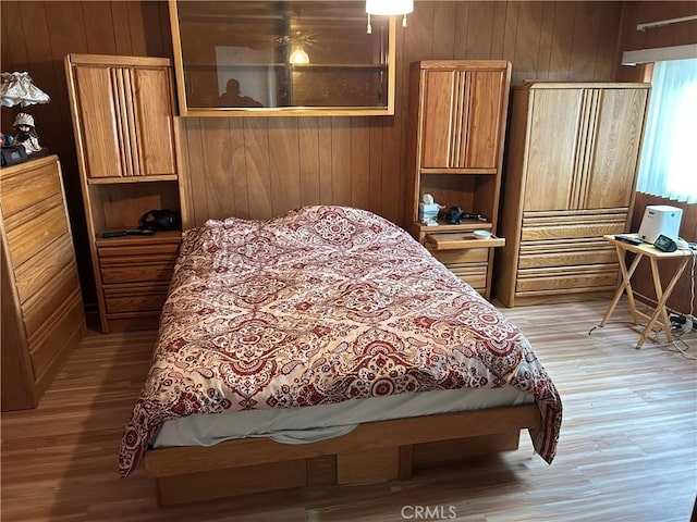 bedroom featuring wooden walls and light wood-type flooring