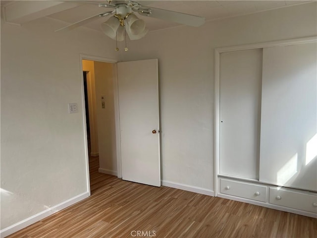 unfurnished bedroom featuring wood finished floors, baseboards, a closet, and ceiling fan