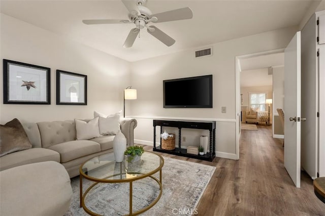 living room with a ceiling fan, baseboards, visible vents, and wood finished floors