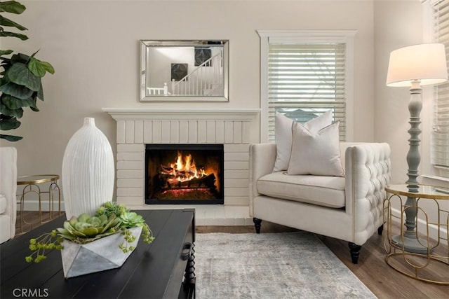living area featuring a brick fireplace and wood finished floors