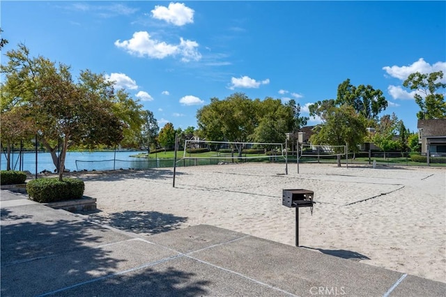 view of property's community featuring volleyball court, fence, and a water view
