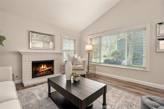 living room featuring baseboards, lofted ceiling, wood finished floors, and a fireplace