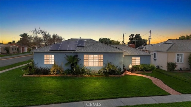 ranch-style house featuring a lawn and solar panels