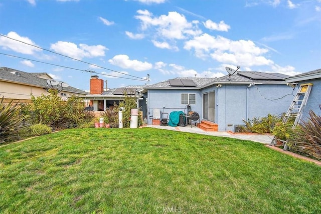 rear view of house featuring a lawn and solar panels