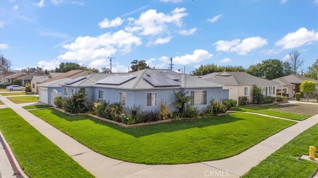 ranch-style house featuring a garage, a front yard, and solar panels