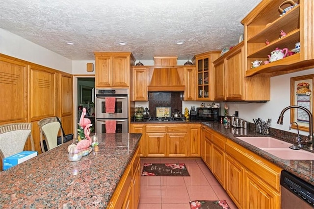 kitchen featuring custom exhaust hood, sink, dark stone countertops, and stainless steel appliances