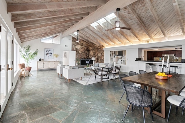 dining space with wood ceiling, ceiling fan, beam ceiling, a skylight, and high vaulted ceiling