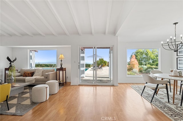 living room featuring beamed ceiling, a chandelier, and light hardwood / wood-style flooring