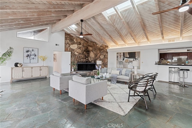 living room with wood ceiling, ceiling fan, beam ceiling, a skylight, and high vaulted ceiling