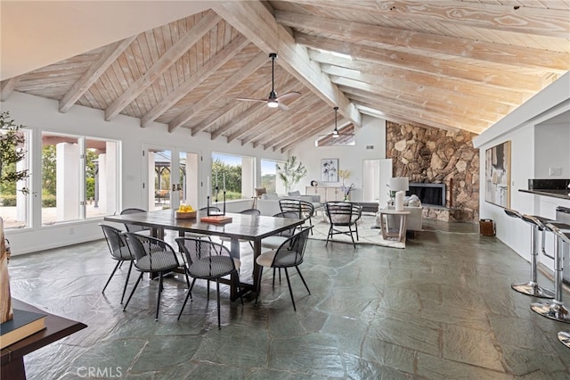 dining area featuring wood ceiling, a skylight, high vaulted ceiling, beamed ceiling, and a fireplace