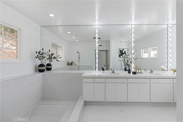 bathroom featuring tile patterned flooring, vanity, and a relaxing tiled tub