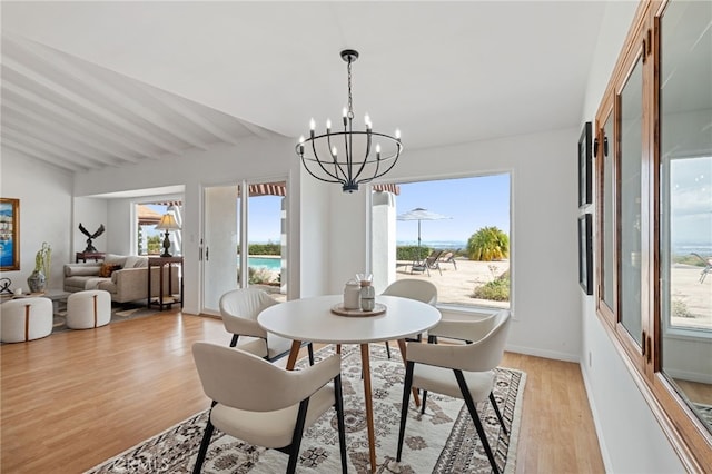 dining area featuring lofted ceiling with beams, a water view, a chandelier, and light hardwood / wood-style flooring