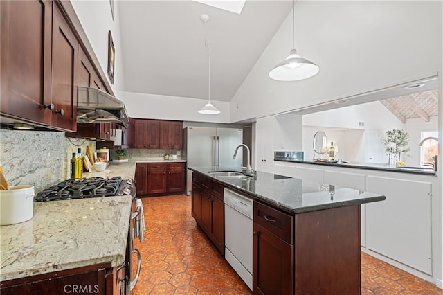 kitchen with appliances with stainless steel finishes, pendant lighting, dark stone countertops, decorative backsplash, and a kitchen island with sink