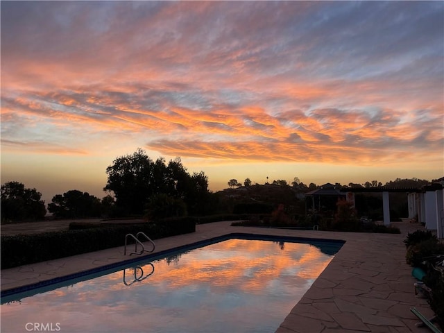 pool at dusk featuring a patio area